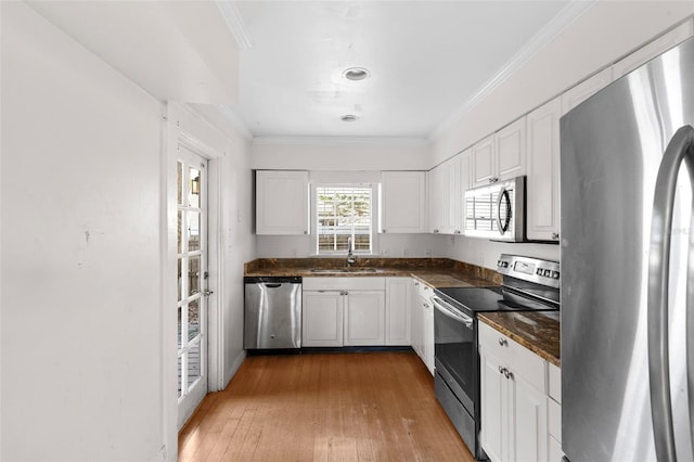 kitchen featuring appliances with stainless steel finishes, dark countertops, crown molding, and a sink