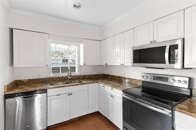 kitchen with stainless steel appliances, white cabinets, a sink, and ornamental molding