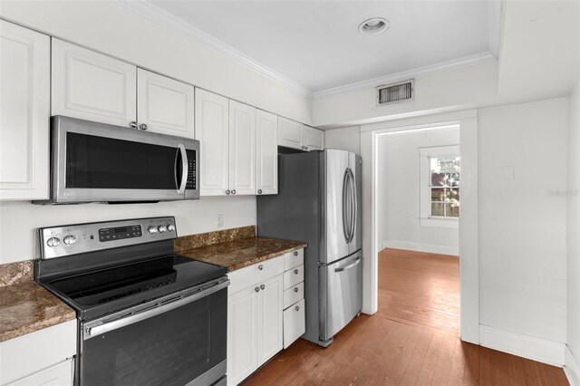 kitchen with stainless steel appliances, white cabinetry, and ornamental molding