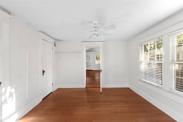 spare room with a wealth of natural light, baseboards, a ceiling fan, and wood finished floors