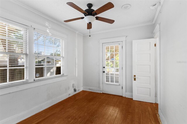 interior space with a wealth of natural light, baseboards, ornamental molding, and wood finished floors