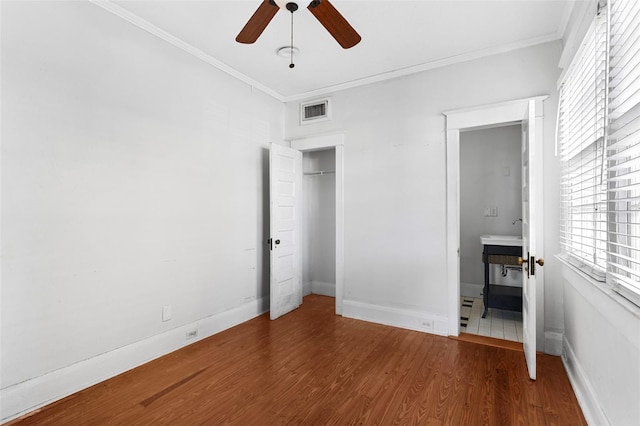 unfurnished bedroom with baseboards, visible vents, wood finished floors, and ornamental molding