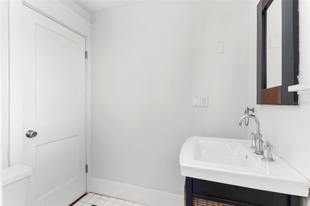 half bath featuring toilet, tile patterned flooring, baseboards, and a sink