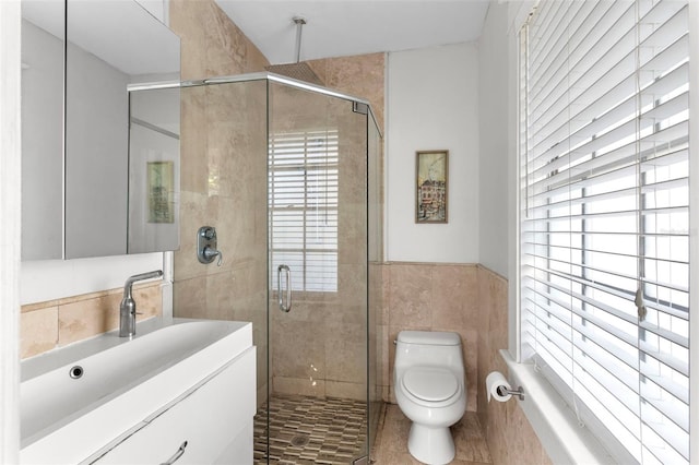 bathroom with toilet, a stall shower, vanity, and tile walls