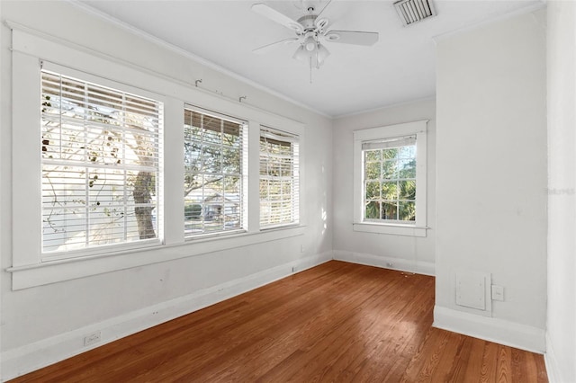 unfurnished room featuring crown molding, visible vents, a ceiling fan, wood finished floors, and baseboards