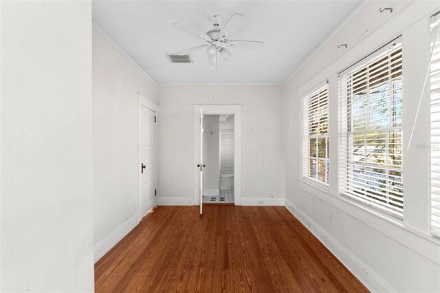 unfurnished room with baseboards, visible vents, crown molding, and wood finished floors