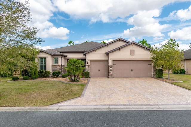 ranch-style house featuring decorative driveway, stucco siding, a front yard, a garage, and stone siding