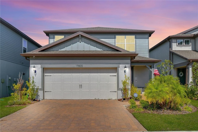 traditional-style house with stucco siding, an attached garage, and decorative driveway