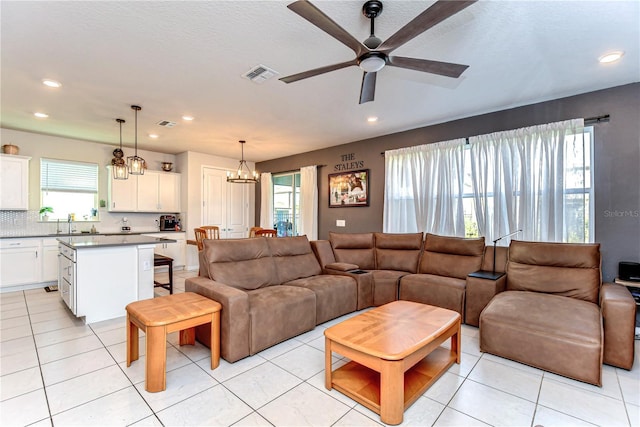 living area with light tile patterned flooring, recessed lighting, visible vents, and ceiling fan with notable chandelier