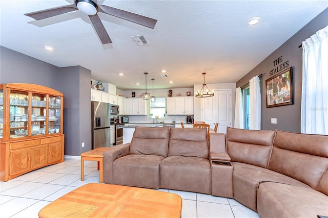 living room featuring a textured ceiling, light tile patterned flooring, visible vents, and recessed lighting