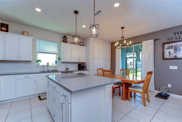 kitchen with visible vents, a sink, backsplash, a center island, and a chandelier