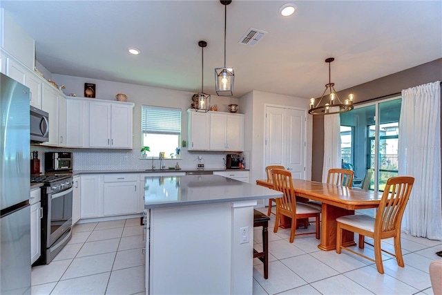 kitchen featuring visible vents, a center island, appliances with stainless steel finishes, a breakfast bar area, and an inviting chandelier