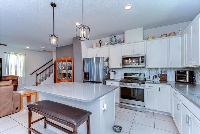 kitchen with light tile patterned floors, stainless steel appliances, tasteful backsplash, and open floor plan
