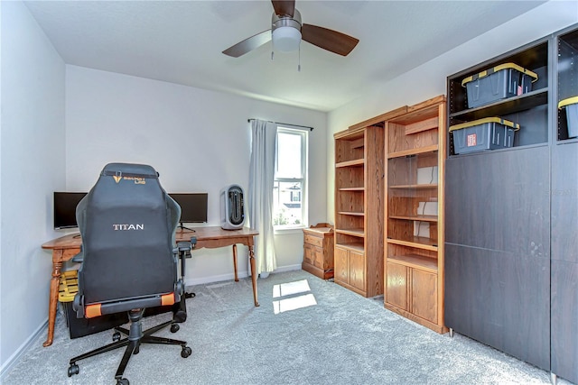 carpeted home office with baseboards and ceiling fan