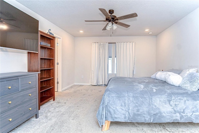 bedroom with a textured ceiling, a ceiling fan, baseboards, and light carpet
