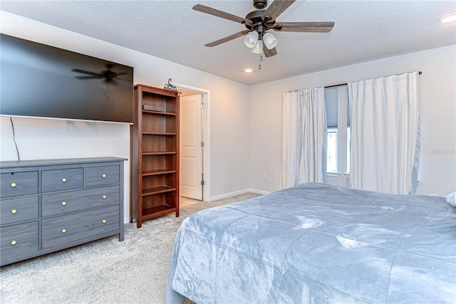 bedroom featuring ceiling fan, light colored carpet, baseboards, and a textured ceiling
