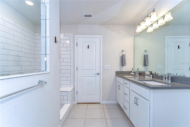 bathroom featuring tile patterned floors, visible vents, tiled shower, and a sink