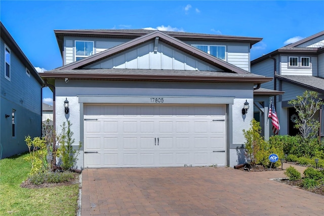 view of front of house with board and batten siding, decorative driveway, and a garage