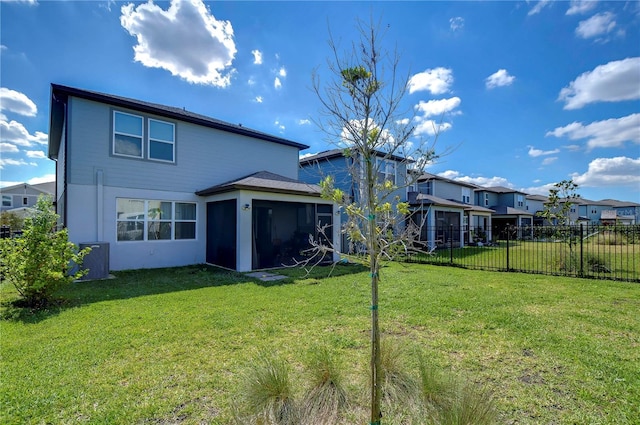 rear view of house featuring fence, a yard, a sunroom, stucco siding, and a residential view