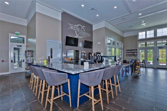 kitchen featuring stone countertops, a high ceiling, french doors, and crown molding