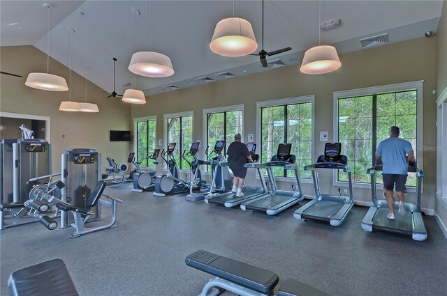 exercise room with visible vents, high vaulted ceiling, and baseboards