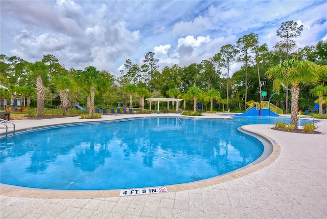 pool featuring a pergola, playground community, and a water slide