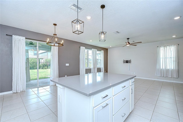 17805 Everlong Dr, Land O Lakes, FL 34638 - kitchen with a center island, light tile patterned flooring, white cabinets, a ceiling fan, and a textured ceiling