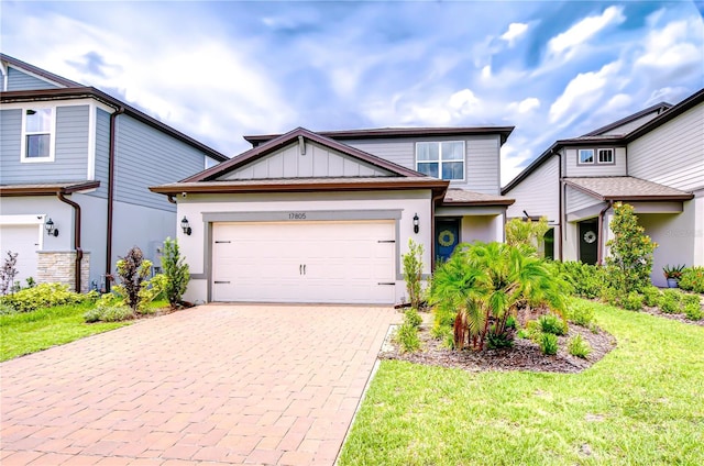 17805 Everlong Dr, Land O Lakes, FL 34638 - view of front of home featuring decorative driveway, an attached garage, a front lawn, and board and batten siding