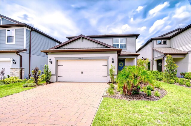 17805 Everlong Dr, Land O Lakes, FL 34638 - view of front of home featuring decorative driveway, an attached garage, a front lawn, and board and batten siding