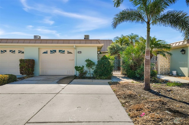 exterior space featuring a gate, concrete driveway, an attached garage, and stucco siding