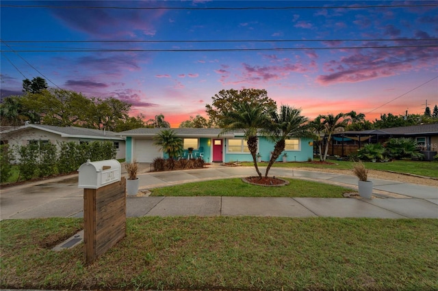 view of front of home with a yard, concrete driveway, and stucco siding