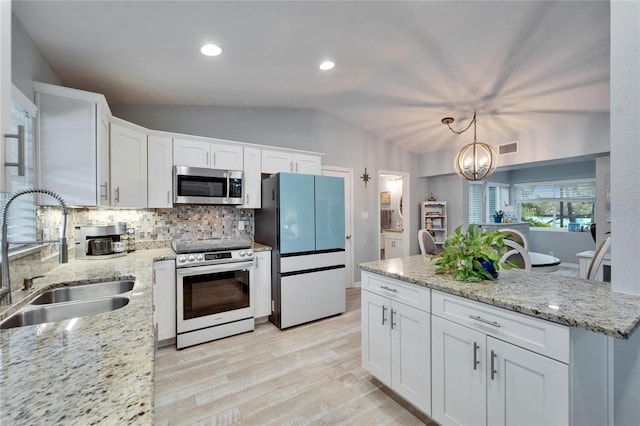 kitchen featuring a sink, backsplash, white cabinetry, appliances with stainless steel finishes, and vaulted ceiling