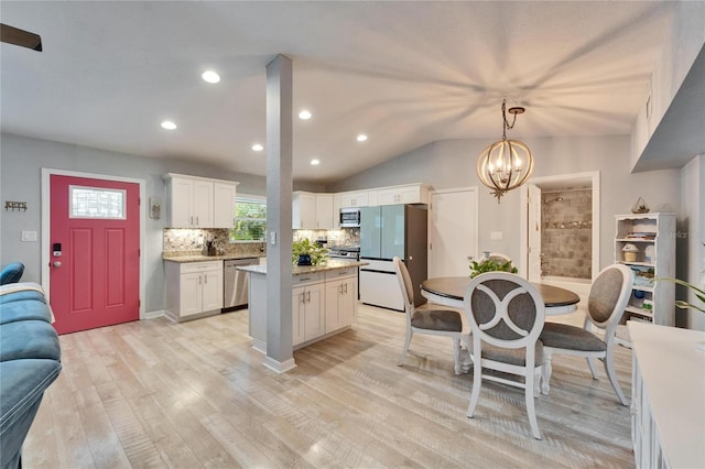 kitchen with light wood-style flooring, a kitchen island, tasteful backsplash, white cabinetry, and appliances with stainless steel finishes