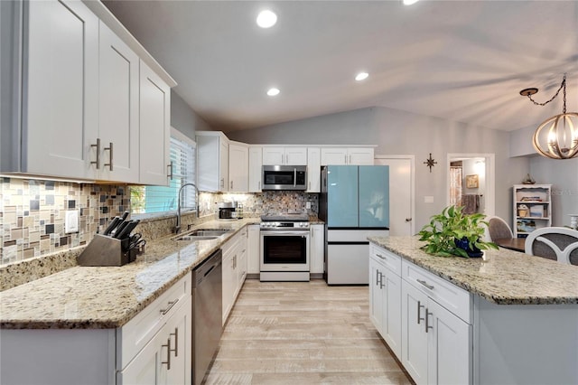 kitchen with a sink, a center island, stainless steel appliances, white cabinets, and lofted ceiling