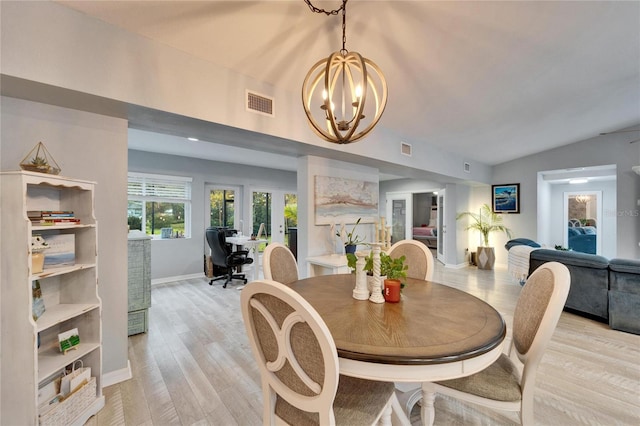 dining room featuring visible vents, a notable chandelier, light wood-style flooring, baseboards, and vaulted ceiling