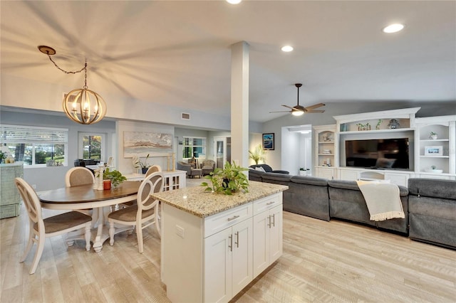 kitchen with light wood-style flooring, open floor plan, white cabinets, light stone countertops, and vaulted ceiling