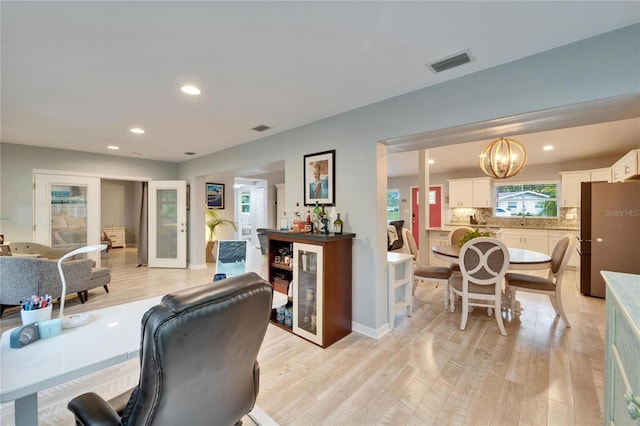 office featuring visible vents, a notable chandelier, recessed lighting, a bar, and light wood finished floors