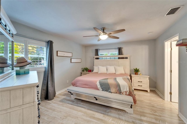 bedroom with visible vents, multiple windows, light wood-style floors, and baseboards