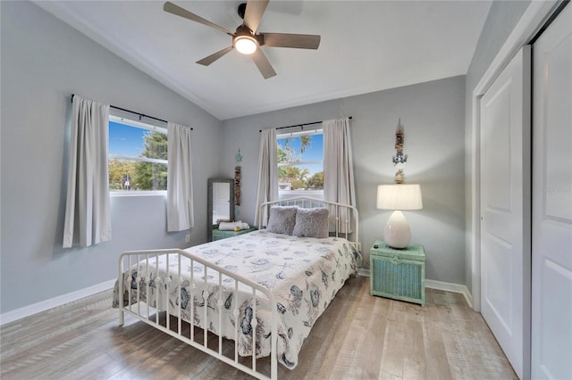 bedroom featuring a closet, multiple windows, lofted ceiling, and wood finished floors