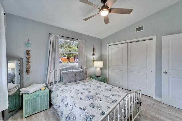 bedroom with a ceiling fan, wood finished floors, visible vents, lofted ceiling, and a closet