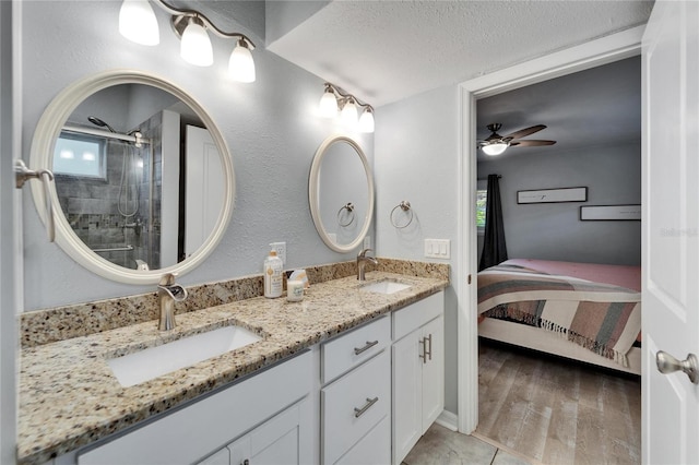 ensuite bathroom featuring tiled shower, a textured ceiling, ensuite bathroom, and a sink