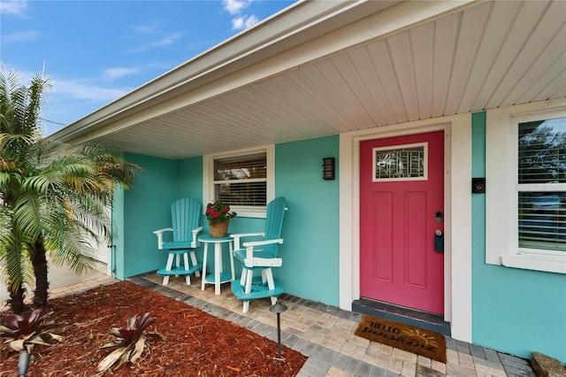 view of exterior entry featuring stucco siding and a porch