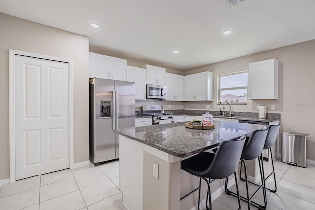 kitchen featuring stainless steel appliances, white cabinets, a sink, and a kitchen breakfast bar