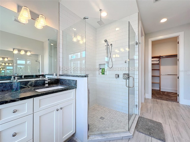 full bathroom featuring a stall shower, a walk in closet, and vanity