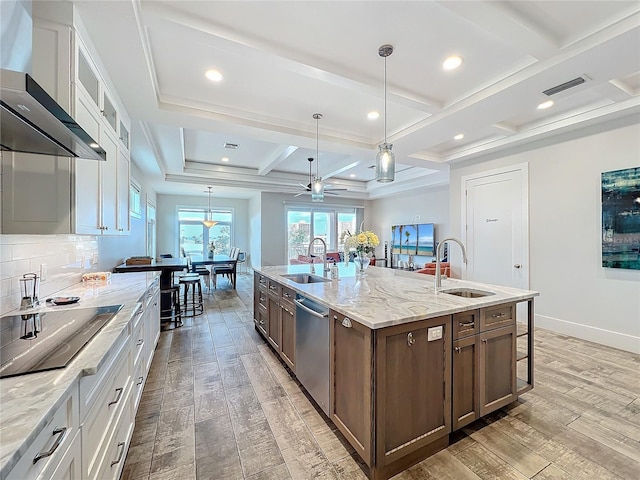 kitchen with light wood-type flooring, wall chimney range hood, stainless steel dishwasher, and a sink