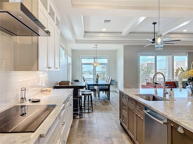 kitchen with black electric stovetop, a sink, stainless steel dishwasher, decorative backsplash, and wall chimney exhaust hood