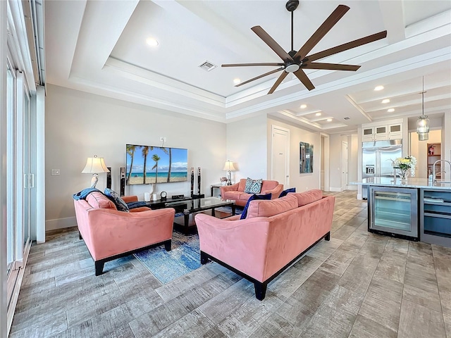 living room with wine cooler, a ceiling fan, visible vents, baseboards, and a raised ceiling