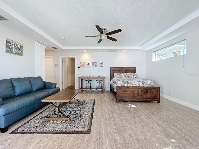 bedroom with a tray ceiling, wood finish floors, visible vents, a textured ceiling, and baseboards