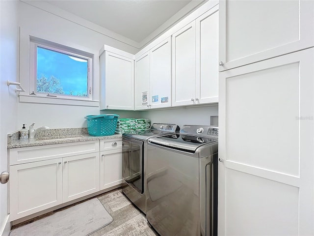 clothes washing area featuring a sink, cabinet space, and washer and dryer