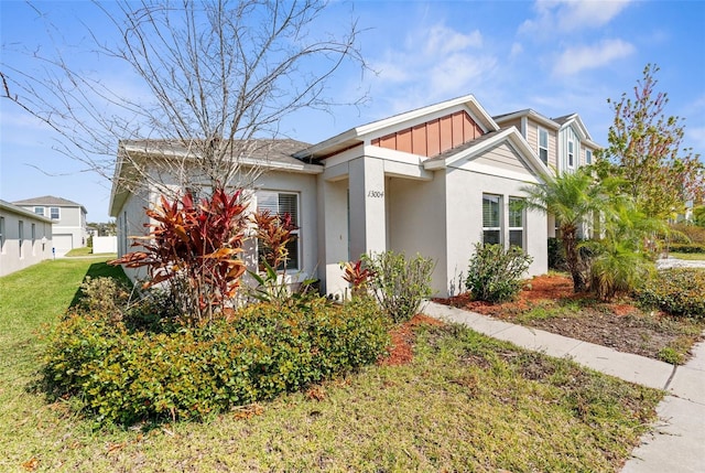 view of front of house with board and batten siding, a front lawn, and stucco siding